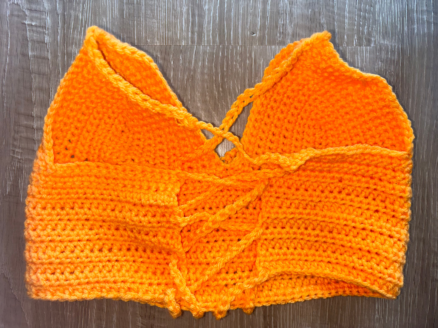 Orange crochet top on a wooden surface