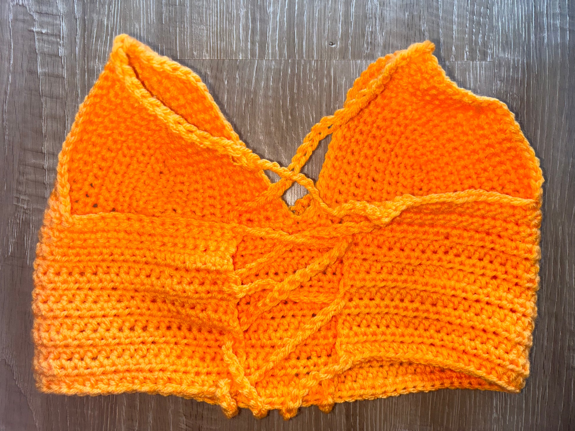 Orange crochet top on a wooden surface