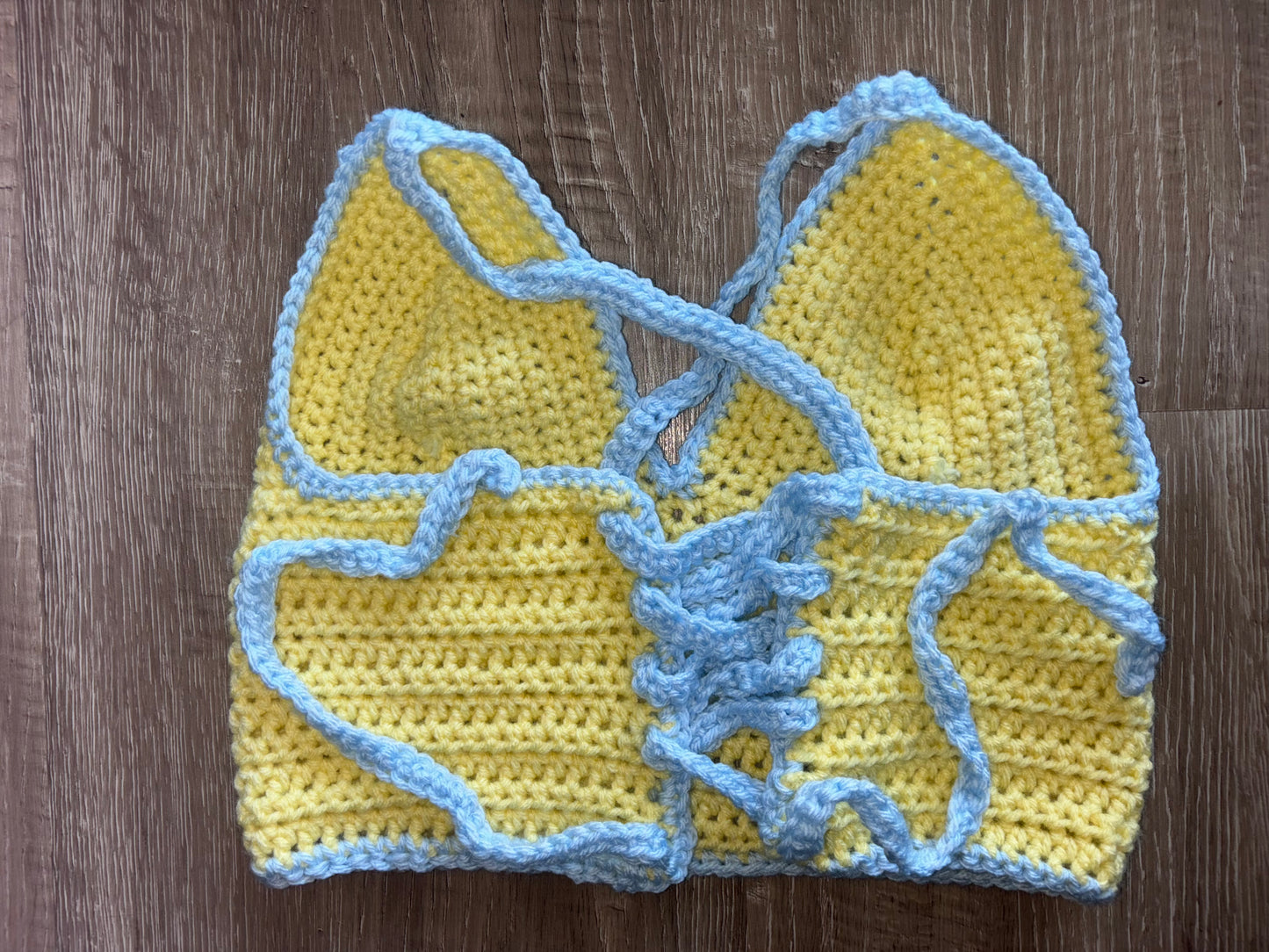 Yellow and blue crocheted top on a wooden surface
