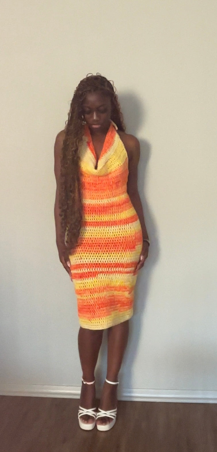Woman wearing a colorful striped crochet dress against a plain background