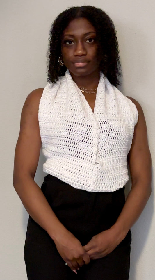 Woman wearing a white crocheted halter top against a plain background