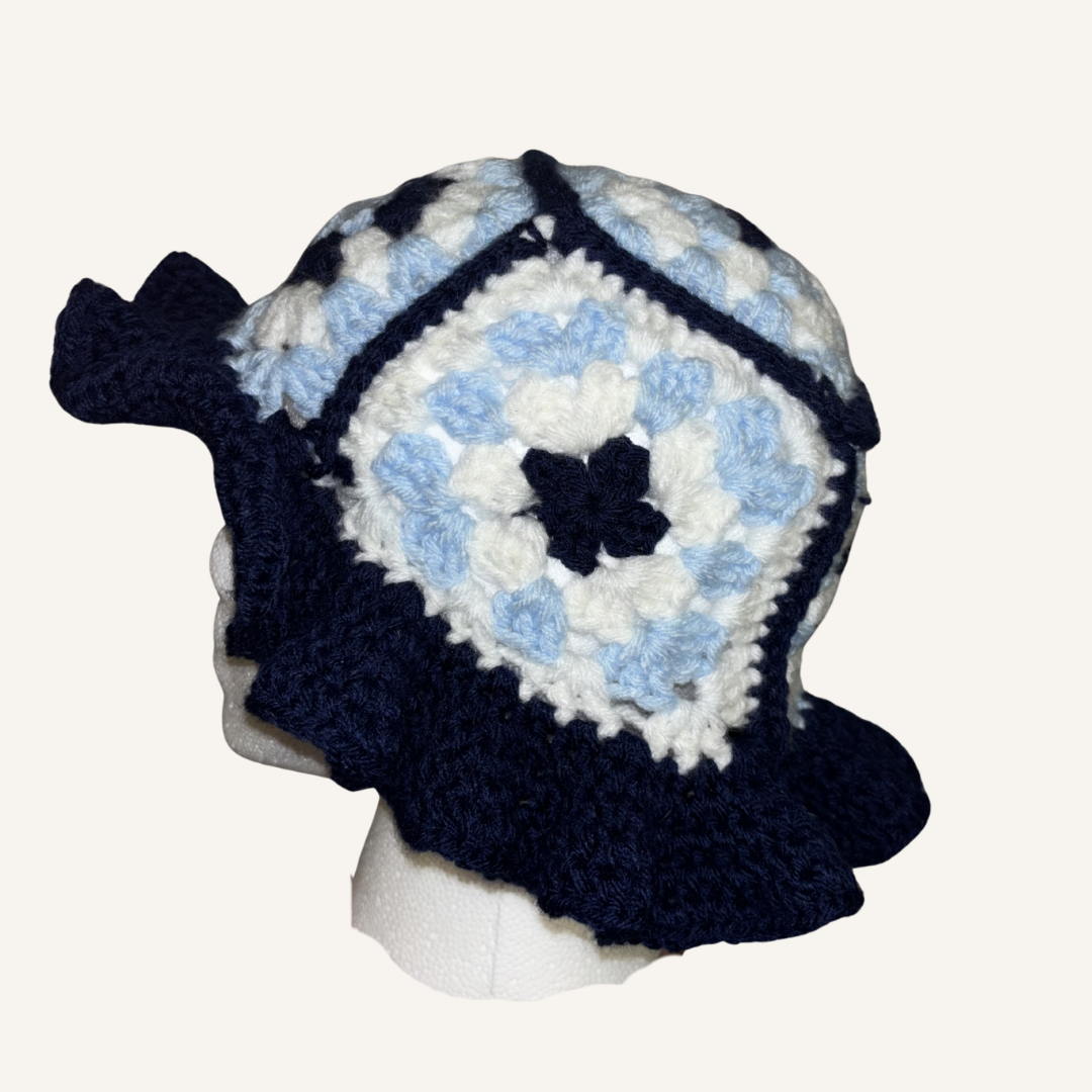 Crocheted bucket hat with blue and white granny square pattern on a mannequin head against a white background