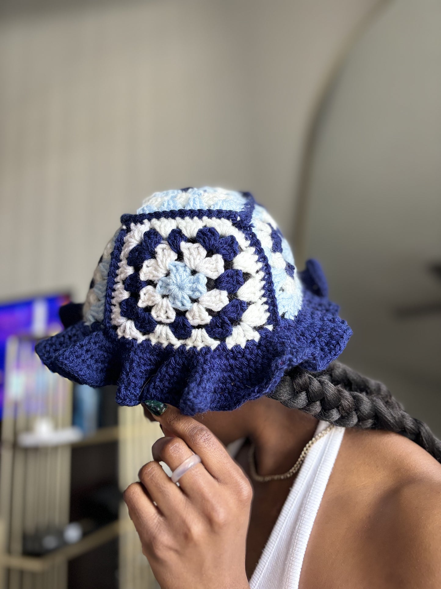 Person wearing a blue and white crocheted hat with a blurred background