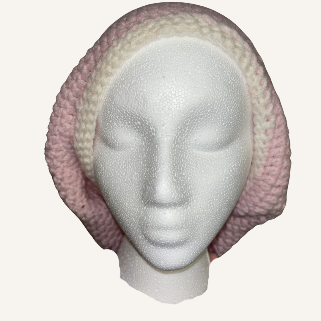 Crocheted pink and beige locsoc hat on a mannequin head against a white background