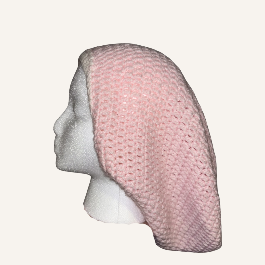 Pink crocheted locsoc hat on a mannequin head against a white background