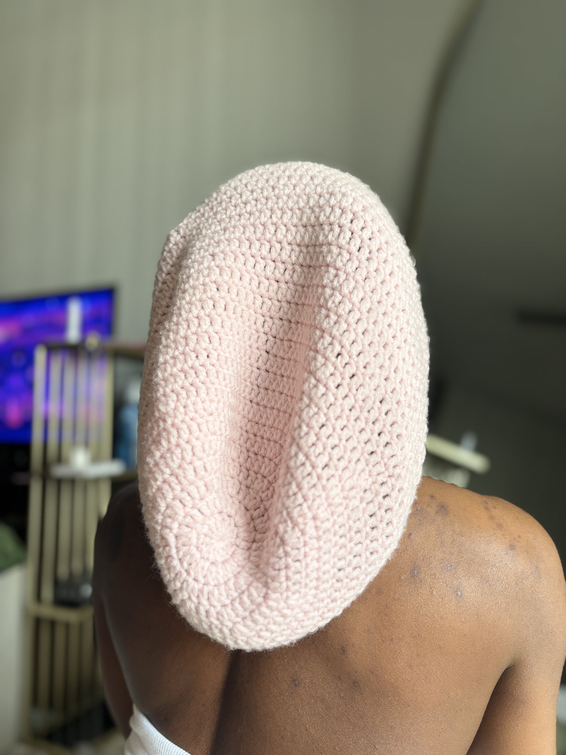 Person wearing a pink crochet locsoc in an indoor setting