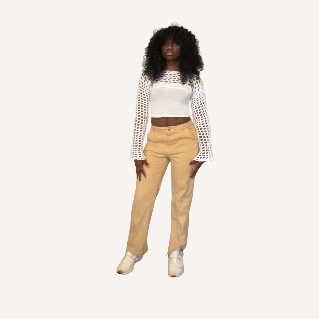 Person wearing a white top with mesh white crochet shrug and beige pants on a white background