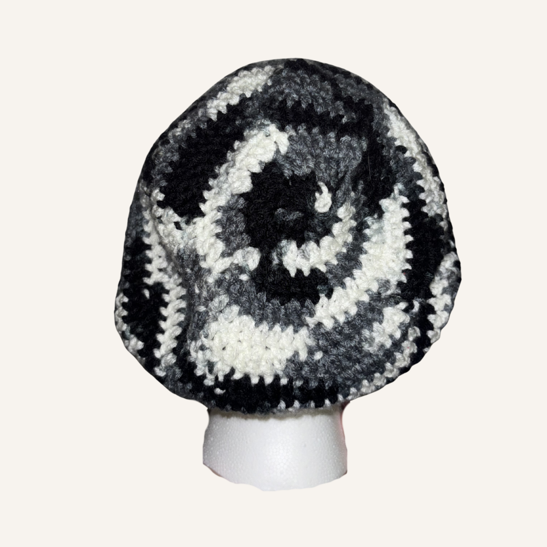Black and white crocheted beret on a mannequin head against a white background