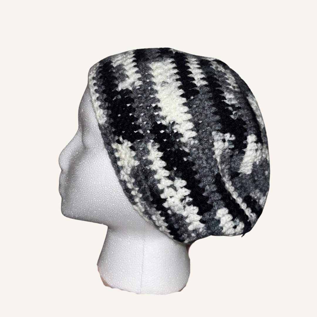 Crocheted beret with black and white pattern on a mannequin head against a white background