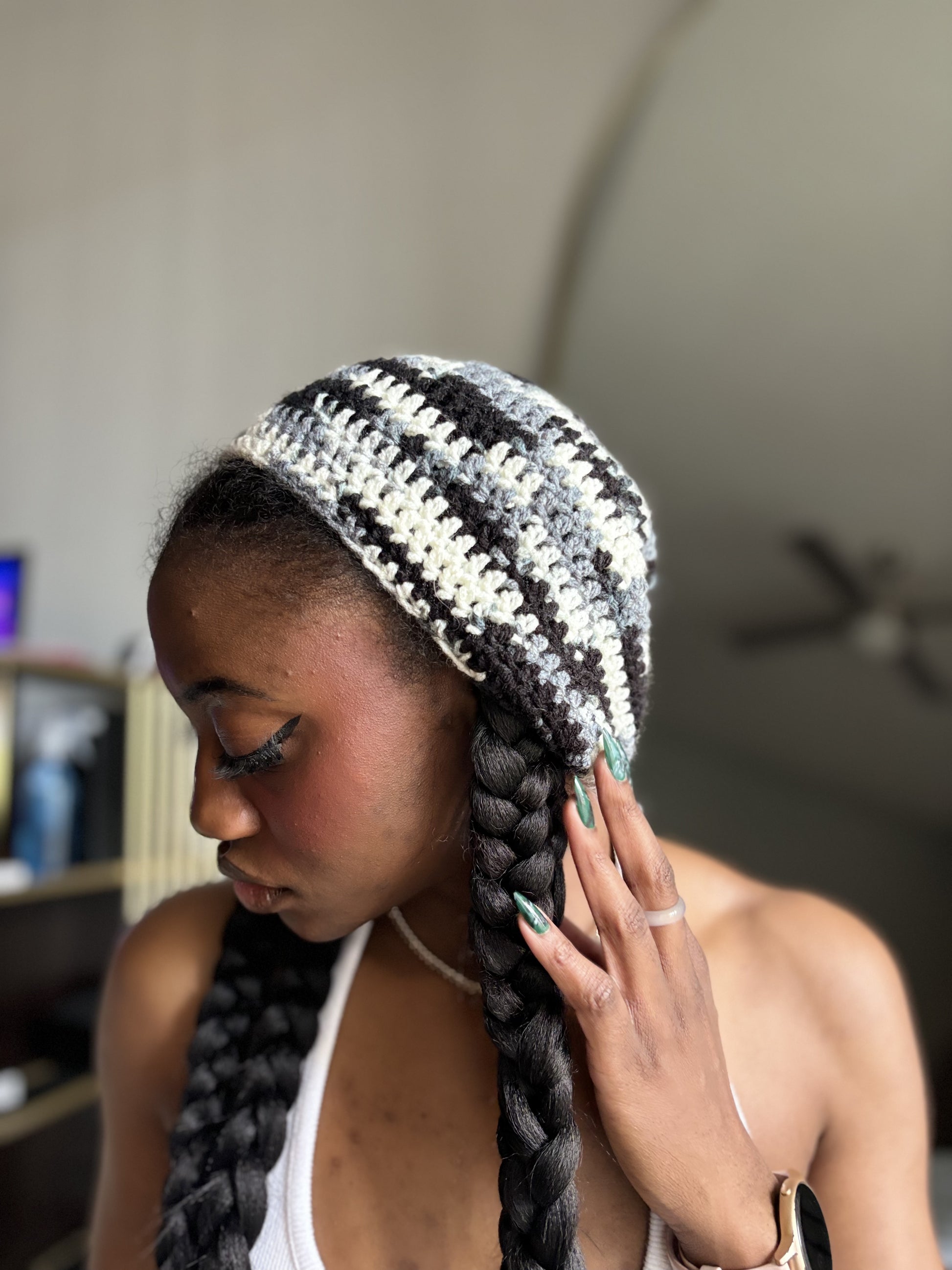 Woman wearing a black and white striped crochet beret with braided hair indoors.