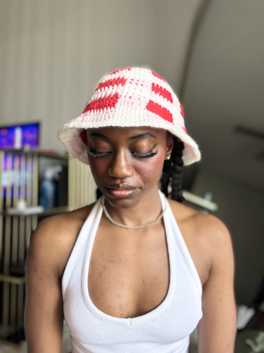 Woman wearing a red, pink and white plaid crocheted bucket hat indoors