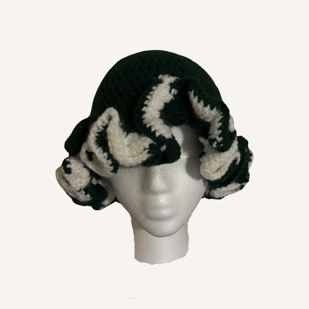 Green and white crochet ruffle hat on a mannequin head against a white background