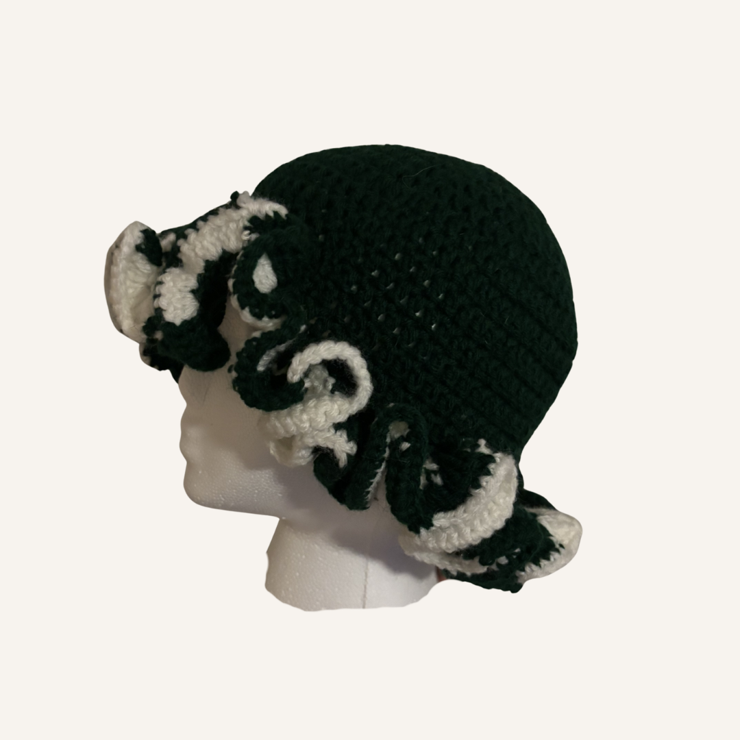 Green and white crocheted ruffle hat on a mannequin head against a white background