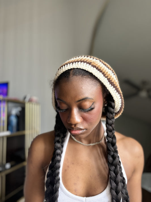 Woman wearing a crocheted striped beret and white tank top in a casual indoor setting